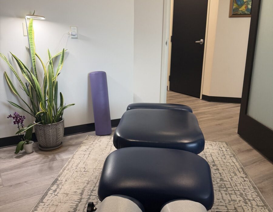 Adjusting table in a bright treatment room with a plant and yoga mat
