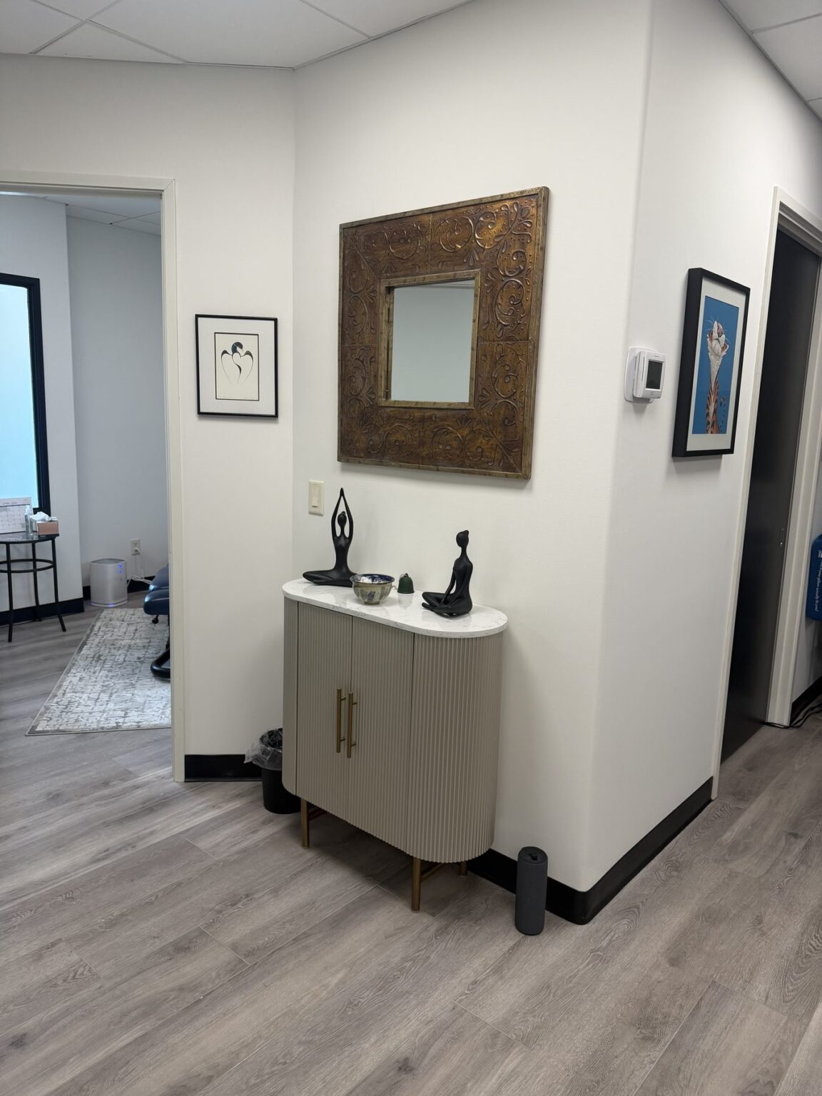 A calm hallway at Hidden Health with a gold-framed mirror and meditation figures